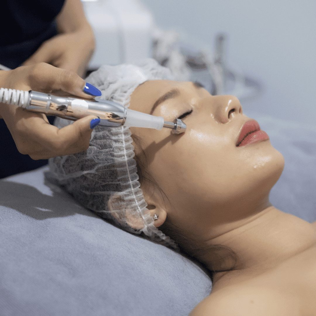 A woman receiving a facial treatment with a dermabrasion tool in a clinic setting.