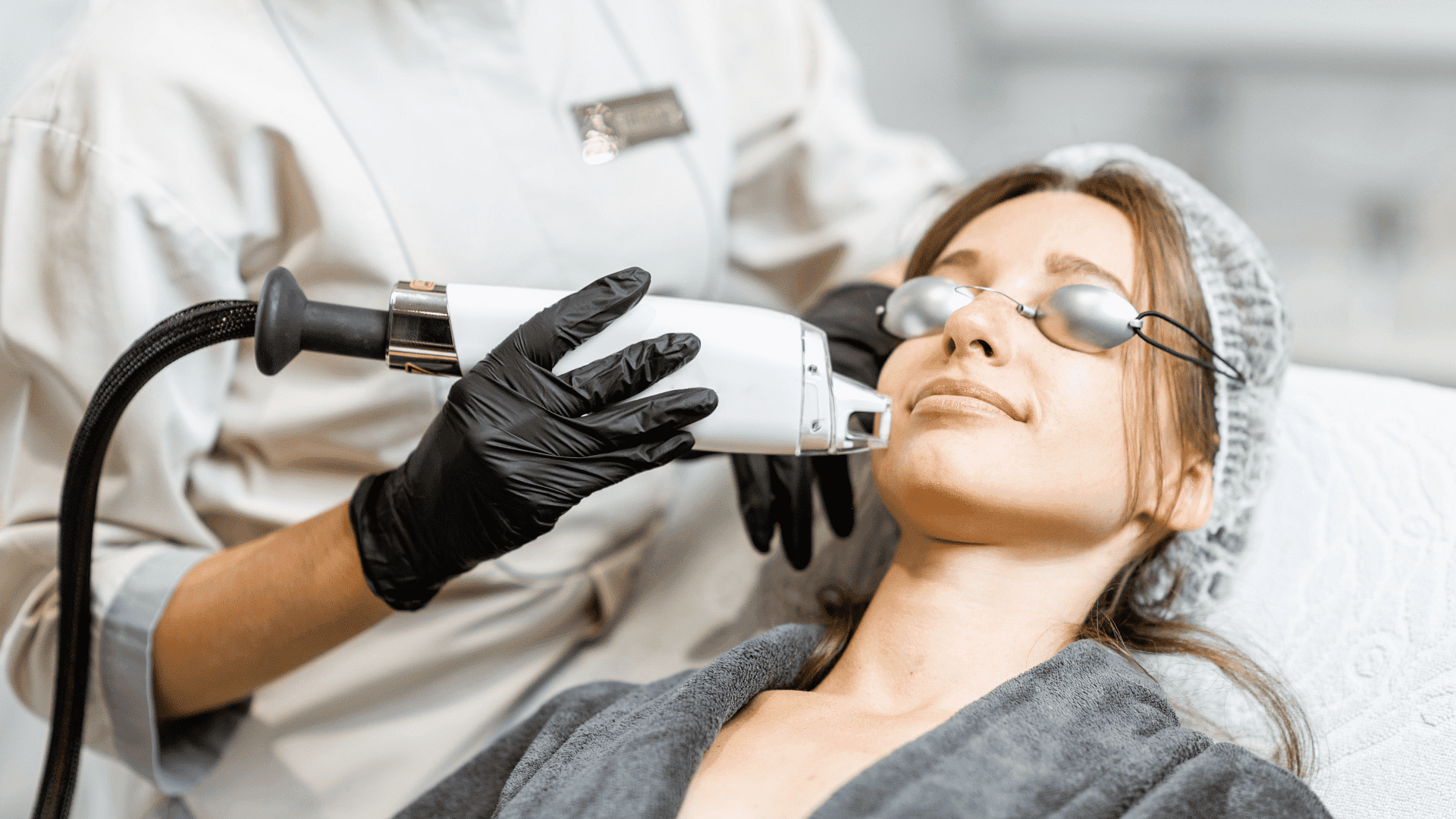 Woman receiving a laser facial treatment from a professional in a clinical setting.