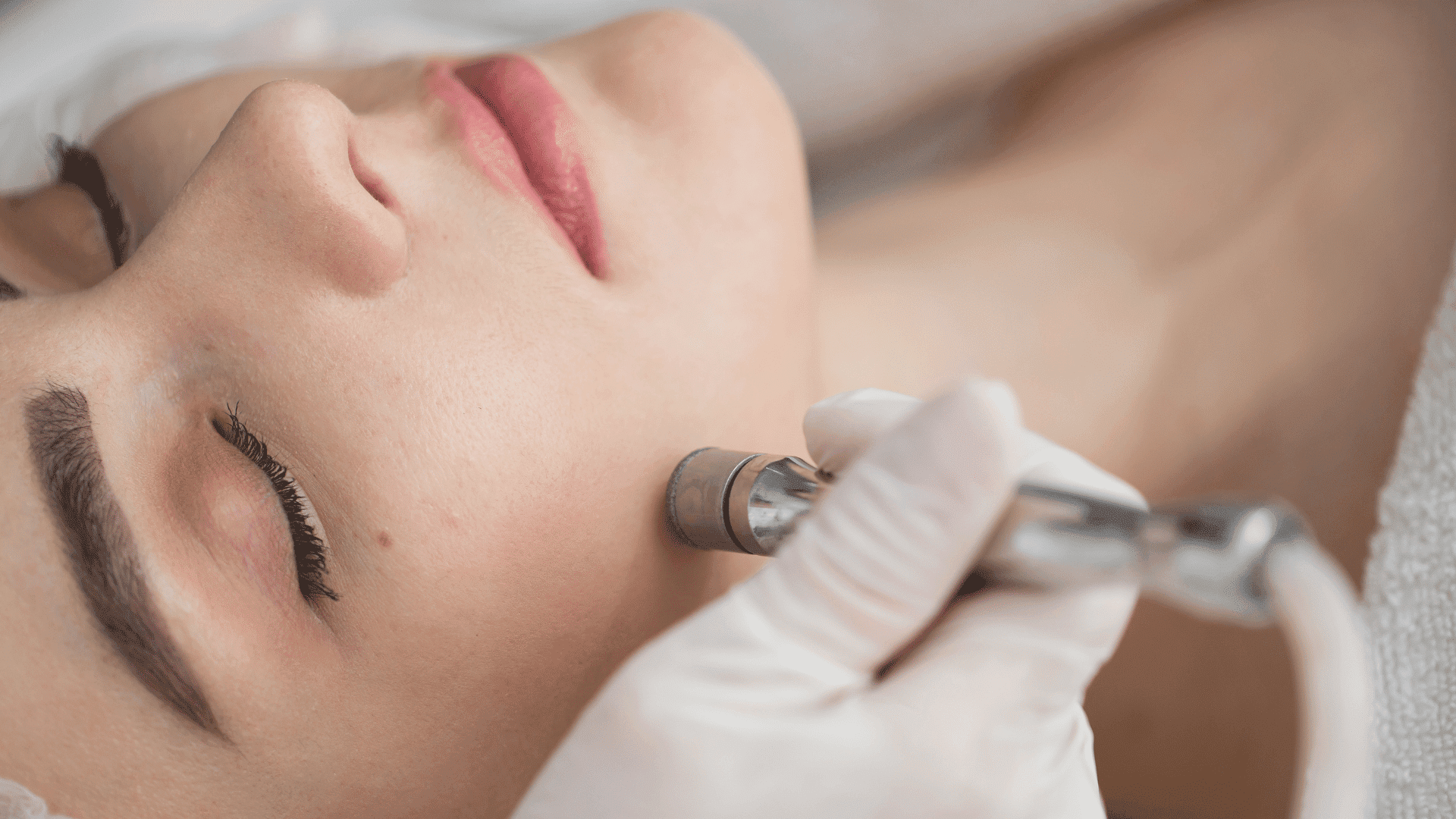 Close-up of a woman receiving a facial skin treatment with a professional tool.